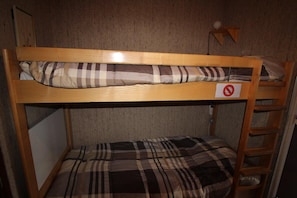 A bunk bed with a 'no smoking' sign, a ladder, and a wall-mounted lamp.