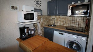 Une cuisine compacte équipée d’un four à micro-ondes, d’un four, d’un évier et d’un lave-linge.