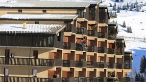 Un hôtel à plusieurs étages, doté de balcons, qui se dresse sur fond de montagnes enneigées.