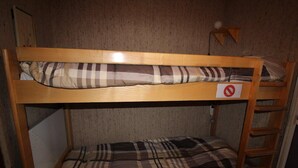 Un lit superposé avec un panneau « interdiction de fumer », une échelle et une lampe fixée au mur.