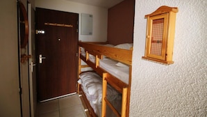A room with a wooden bunk bed, a door, and a small window with a wooden frame. - View mountain, balcony, parking, tv, ski locker, 23m², Auris en Oisans (Auris)