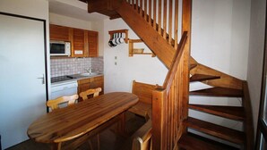 A kitchen with wooden cabinets, a microwave, and a dining area with a wooden table and chairs.