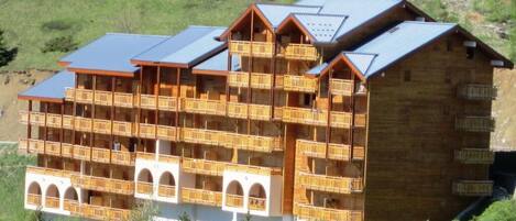A multi-story wooden building with balconies, likely a hotel or lodge, set in a mountainous area.