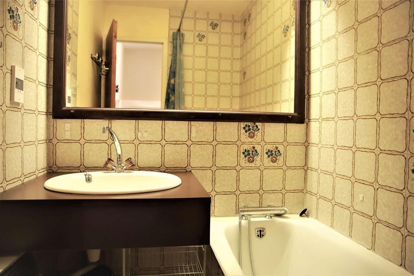 A bathroom with a white sink, a mirror, and a bathtub.