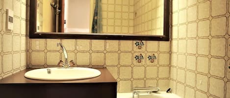A bathroom with a white sink, a mirror, and a bathtub.