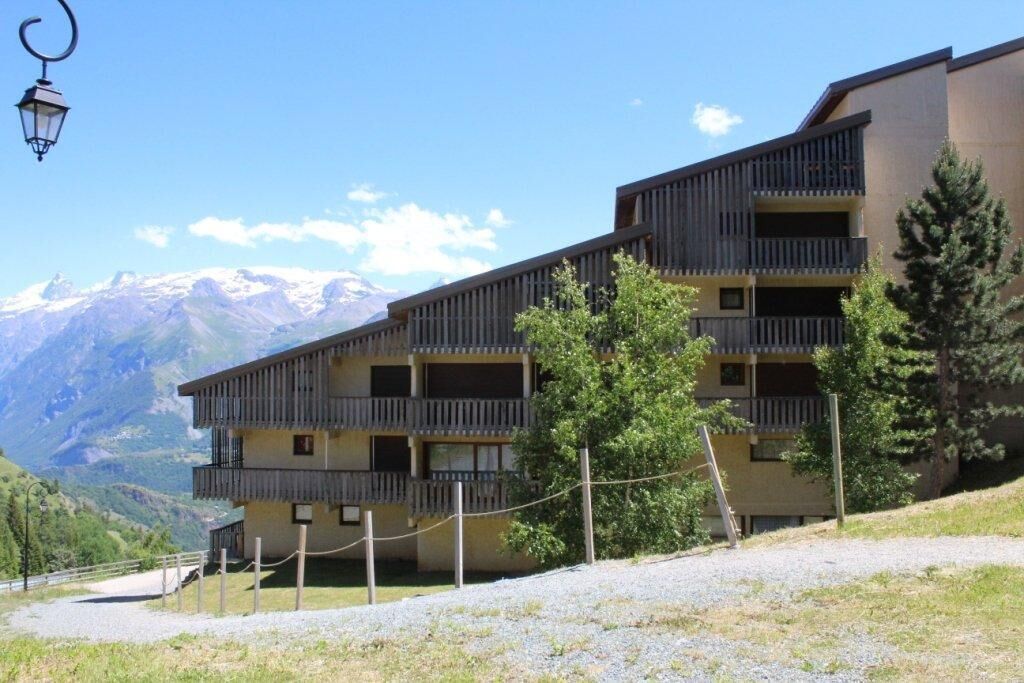 Ein mehrstöckiges Gebäude mit Balkonen, eingebettet in eine gebirgige Landschaft.