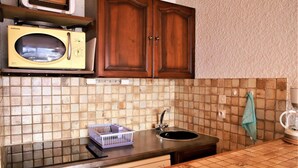 A kitchen with a microwave, sink, and wooden cabinets.