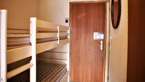 A room with bunk beds, a wooden door with a lock, and a mirror on the wall.