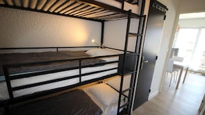 Habitación con literas, un escritorio, una silla, una puerta y vistas al exterior.
