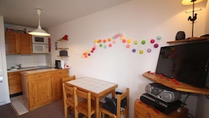 Une cuisine compacte dotée de meubles en bois, d’un four à micro-ondes, d’un évier et d’une table à manger avec des chaises.