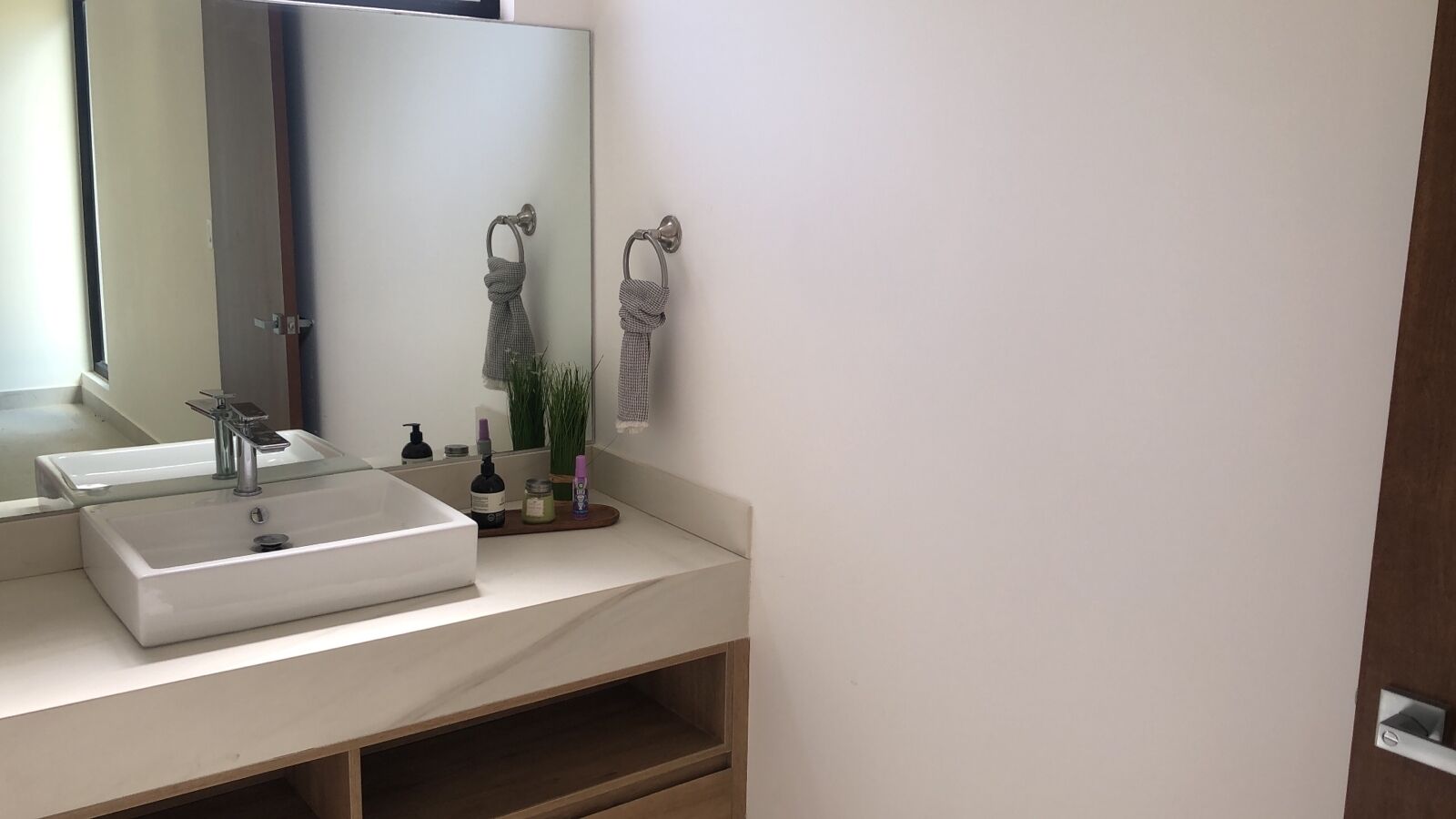 Een badkamer met een witte wastafel, een spiegel en een houten plank.