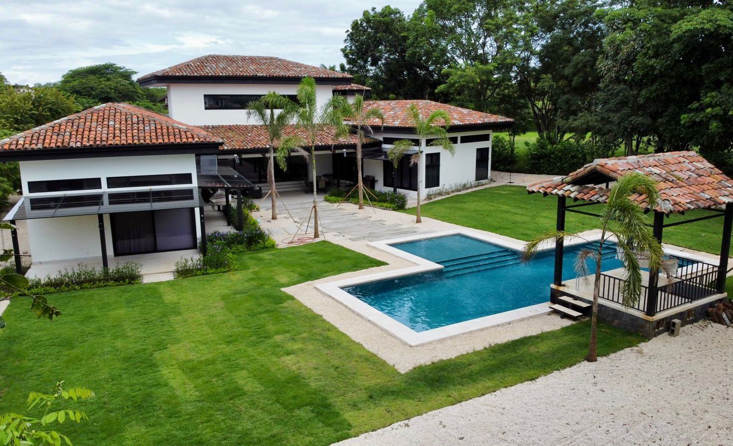 A residential property with a swimming pool, two houses, and a gazebo.