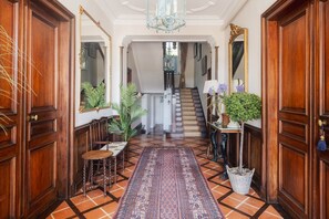 Ein Flur mit Holztüren, einer Treppe, einem gemusterten Teppich und einem Blumentopf.