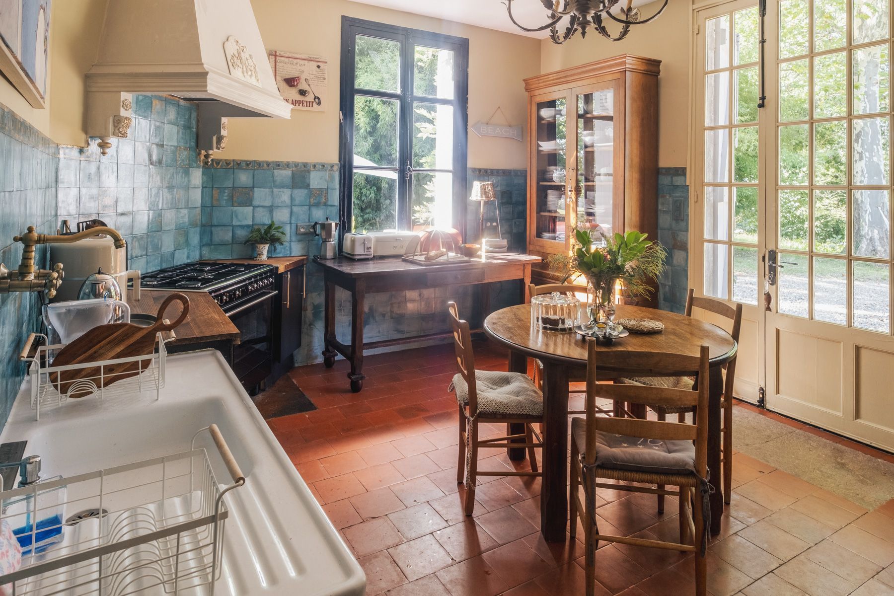A kitchen with a stove, sink, and dining table with chairs.