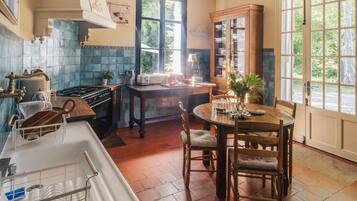 A kitchen with a stove, sink, and dining table with chairs.