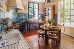 Une cuisine équipée d’une cuisinière, d’un évier et d’une table à manger avec des chaises.