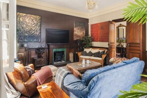 Ein Wohnzimmer mit Kamin, Sofa, Ledersessel und Fernseher.