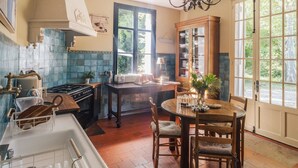 A kitchen with a stove, sink, and dining table with chairs.