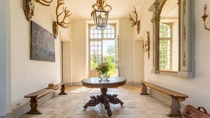 A hallway with a round table, benches, and antler decorations.