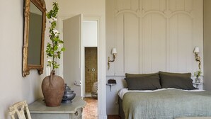 A bedroom with a bed, bedside tables, a dresser, a mirror, and a door leading to a bathroom.