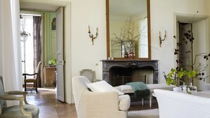 A living room with a fireplace, two armchairs, a sofa, and a mirror.