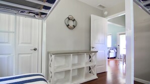 A bedroom with a bed, a white console table, and a door leading to another room. - JOMO Tri Terrace - Units 2 & 3 (Rocky Mount)