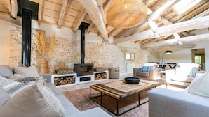 Ein gemütliches Wohnzimmer mit Steinwand, Kamin und rustikalen Holzbalken.
