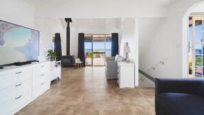 Un salon moderne doté d’un téléviseur à écran plat, de meubles blancs, d’une cheminée et donnant sur un balcon.