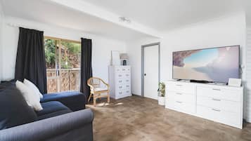 Un salon moderne avec un canapé, un téléviseur et une grande fenêtre agrémentée de rideaux.
