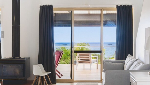 Une pièce dotée d’une grande porte-fenêtre coulissante donnant sur un balcon avec vue sur l’océan.