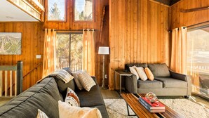 A wooden interior with a sofa, a table with books, and a lamp. - Pet Friendly + Ski In Out Unobstructed Views (Big Bear Lake)