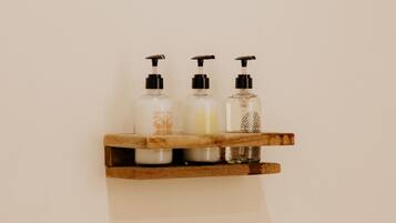 Une étagère en bois sur laquelle sont posées trois bouteilles en verre contenant des produits de toilette.