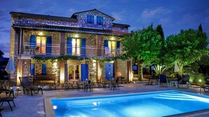 A two-story stone building with a swimming pool, outdoor seating, and a well-lit balcony. - Very nice detached country house TOPAZ near Porec, climate, 5 min. to the sea (Porec)