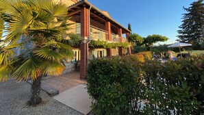 A two-story building with a brick facade, a balcony, and a garden area with palm trees and shrubs. - Very nice detached country house TOPAZ near Porec, climate, 5 min. to the sea (Porec)