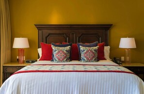 A hotel room with a large bed, two bedside tables with lamps, and a wooden headboard.