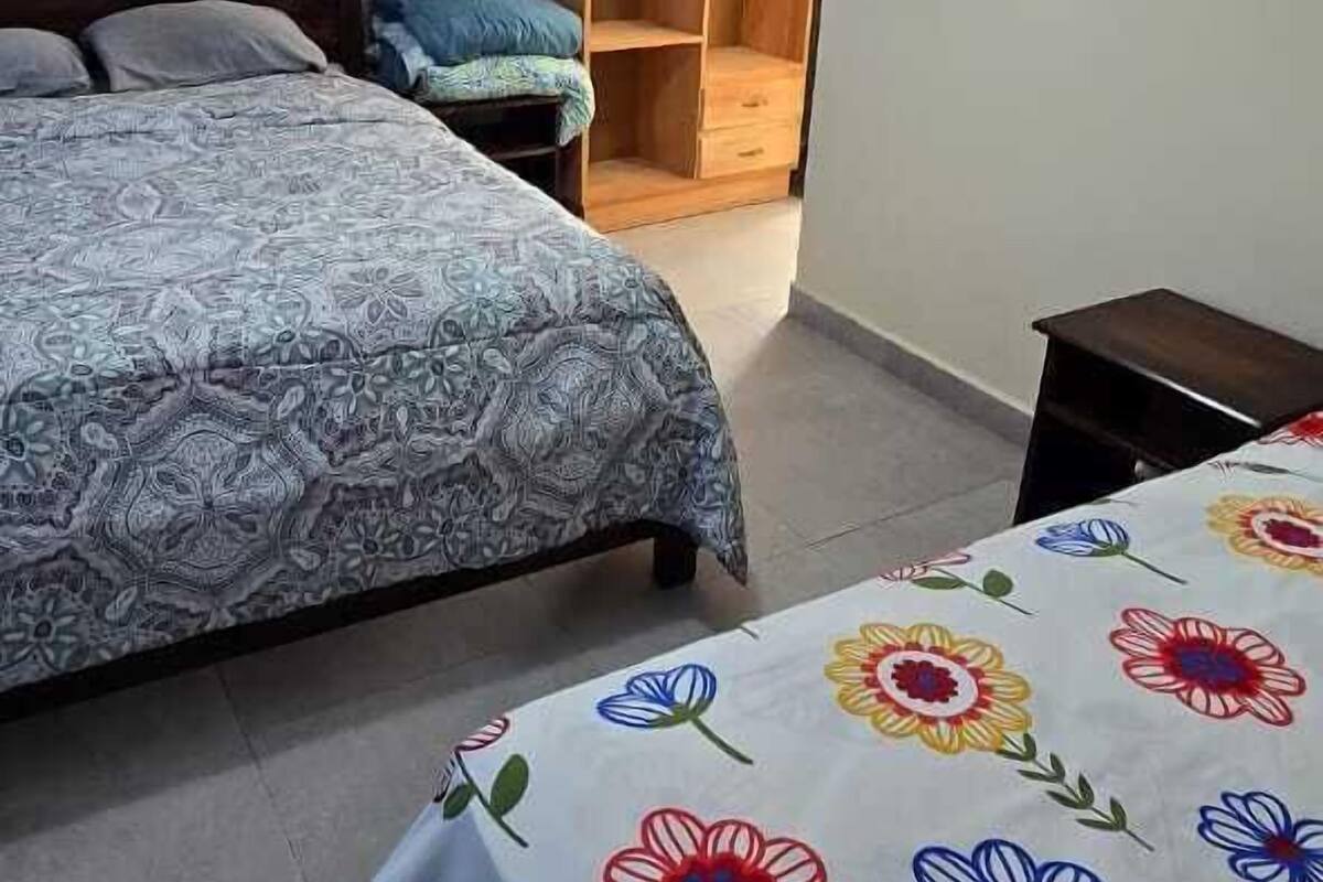 Une chambre avec deux lits, une armoire en bois et un luminaire fixé au plafond.