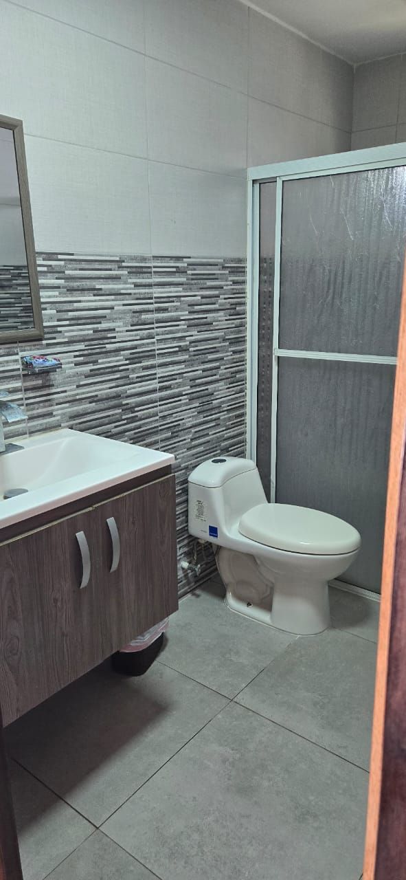 A bathroom with a white sink, wooden cabinet, and a toilet.