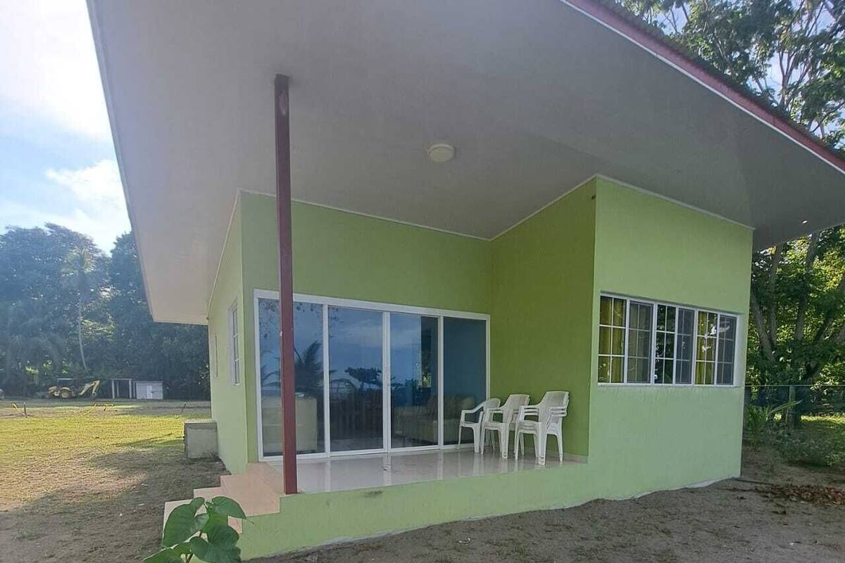 Un bâtiment moderne doté d’un toit plat, de grandes fenêtres et d’un patio couvert avec des chaises.