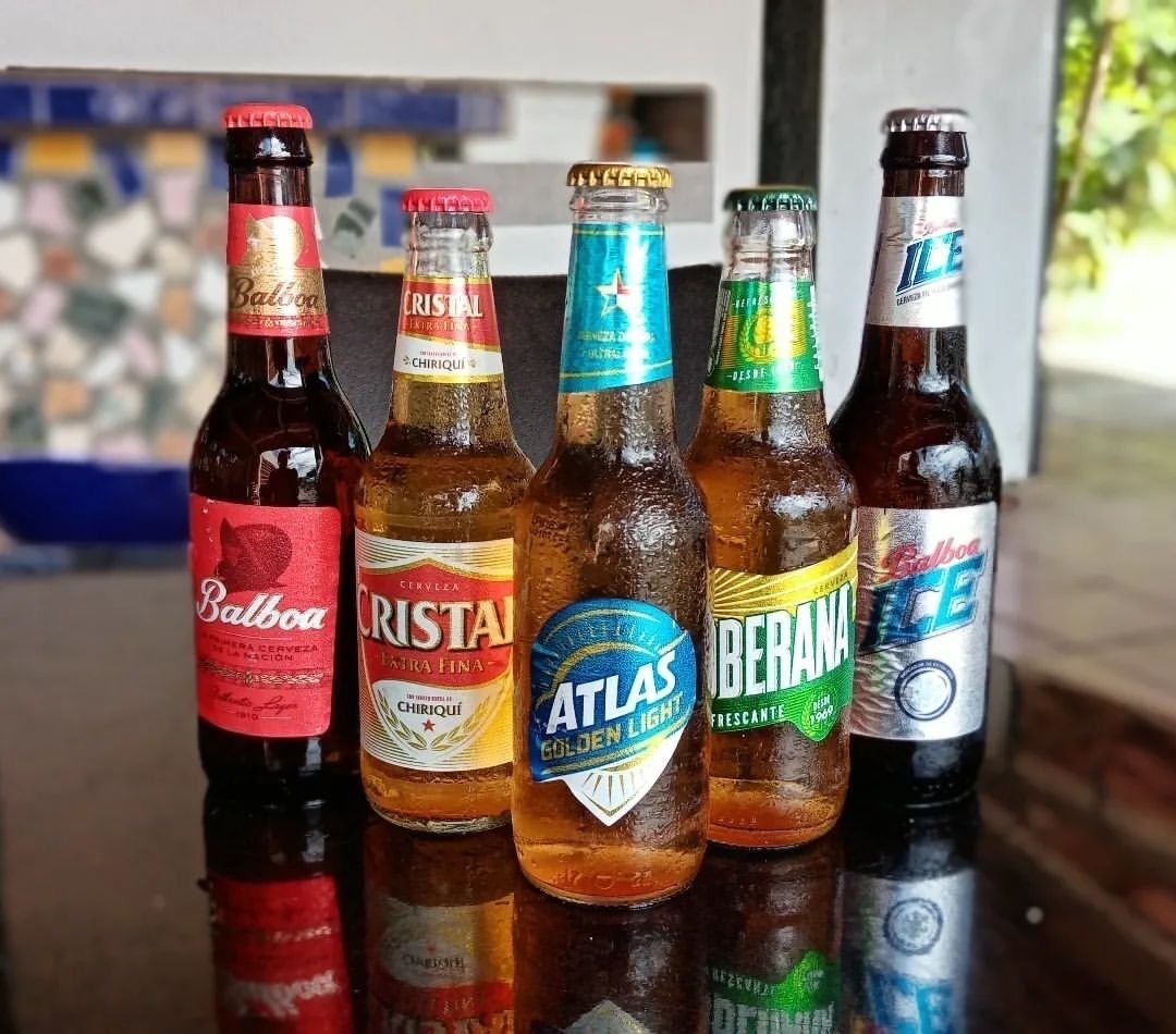 Five bottles of beer on a reflective surface.