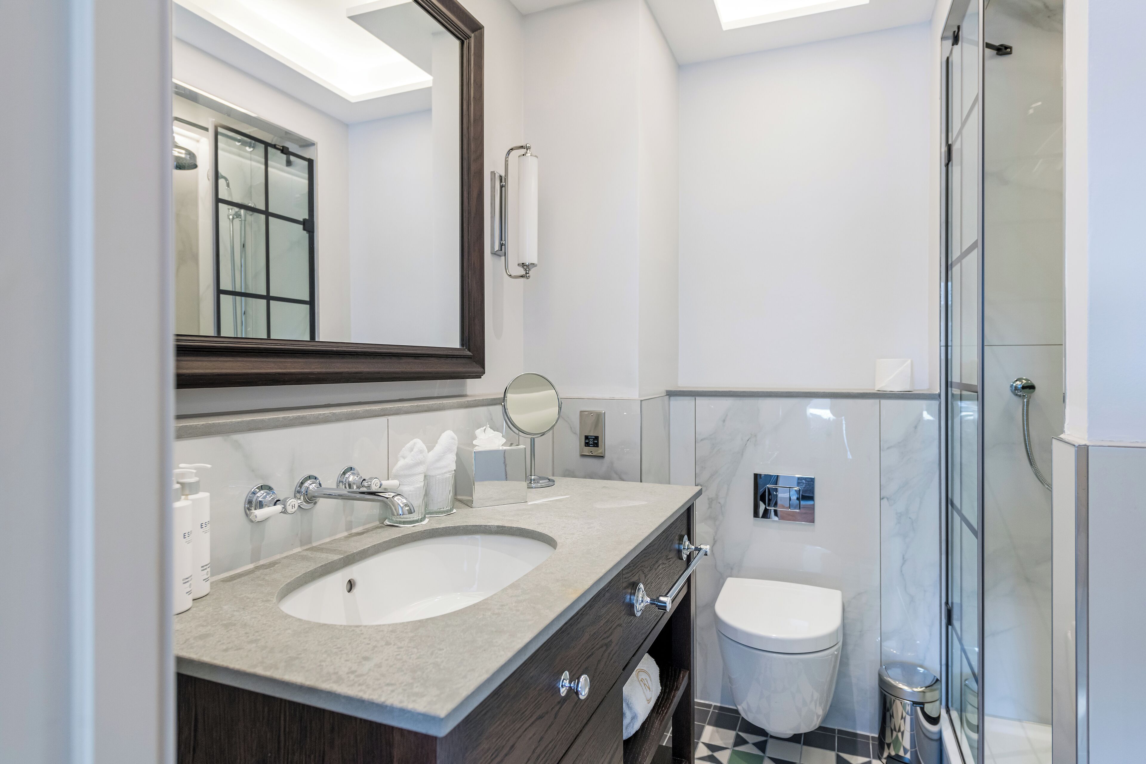 A modern bathroom with a large sink, mirror, and glass shower enclosure.