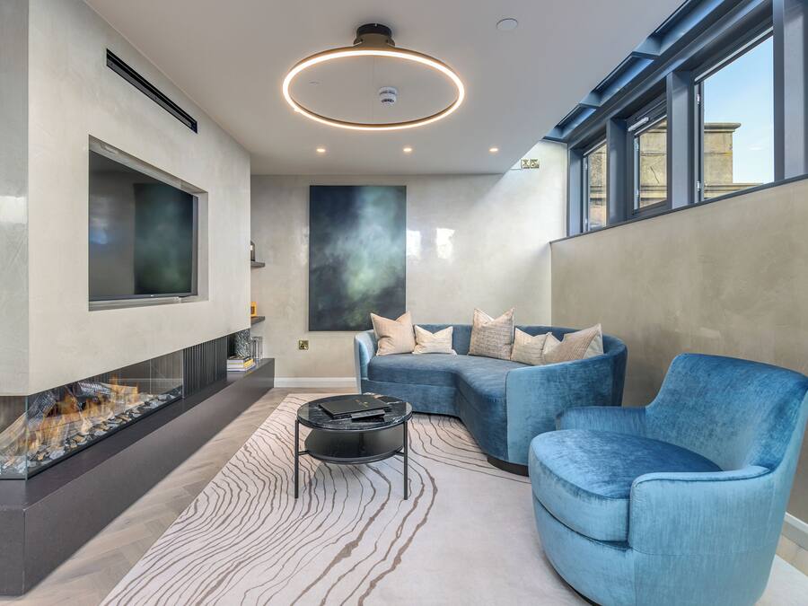Una sala moderna con chimenea, muebles azules y un ventanal grande.