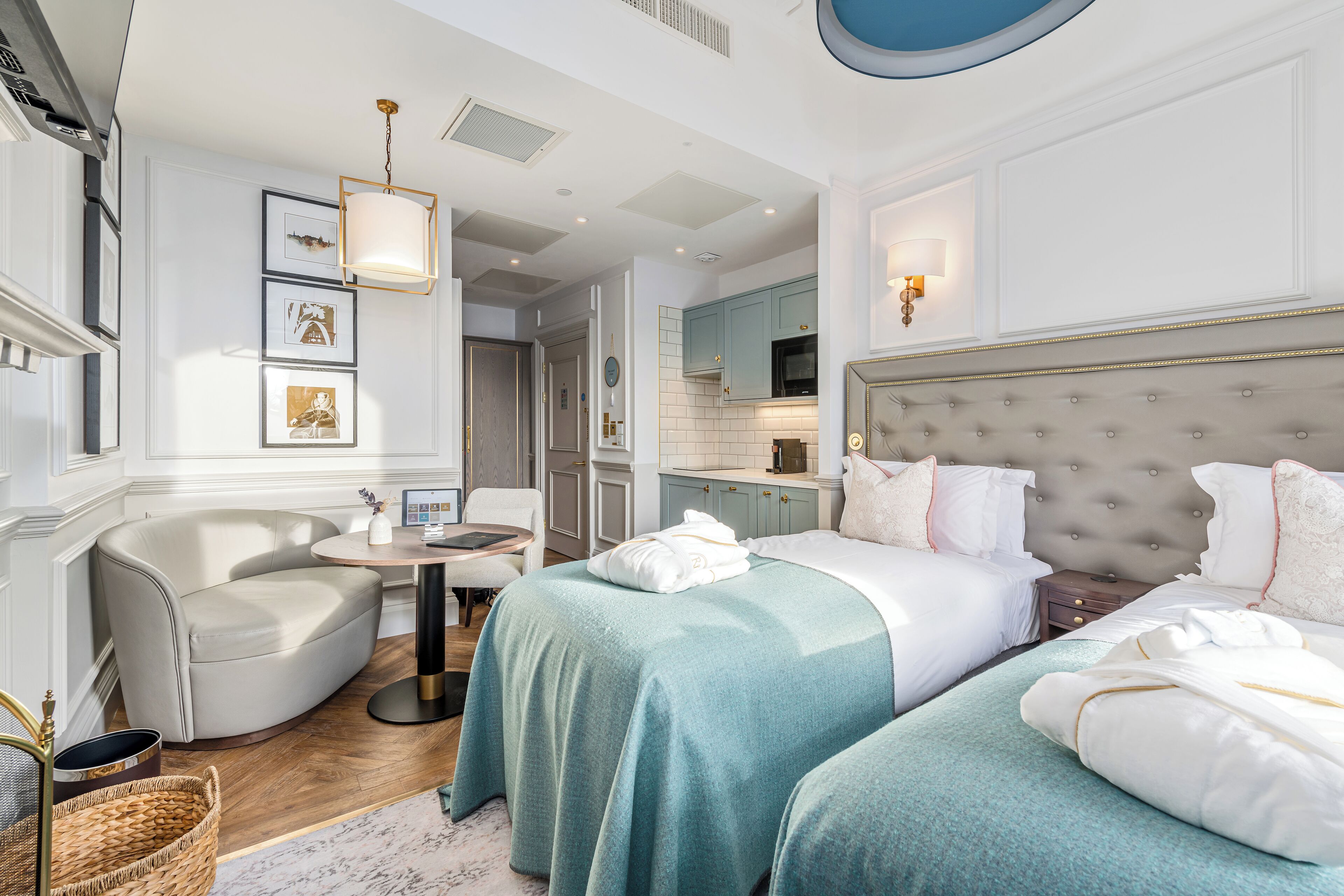 Een moderne hotelkamer met een groot bed, twee nachtkastjes, een zithoek met een stoel en een eettafeltje.