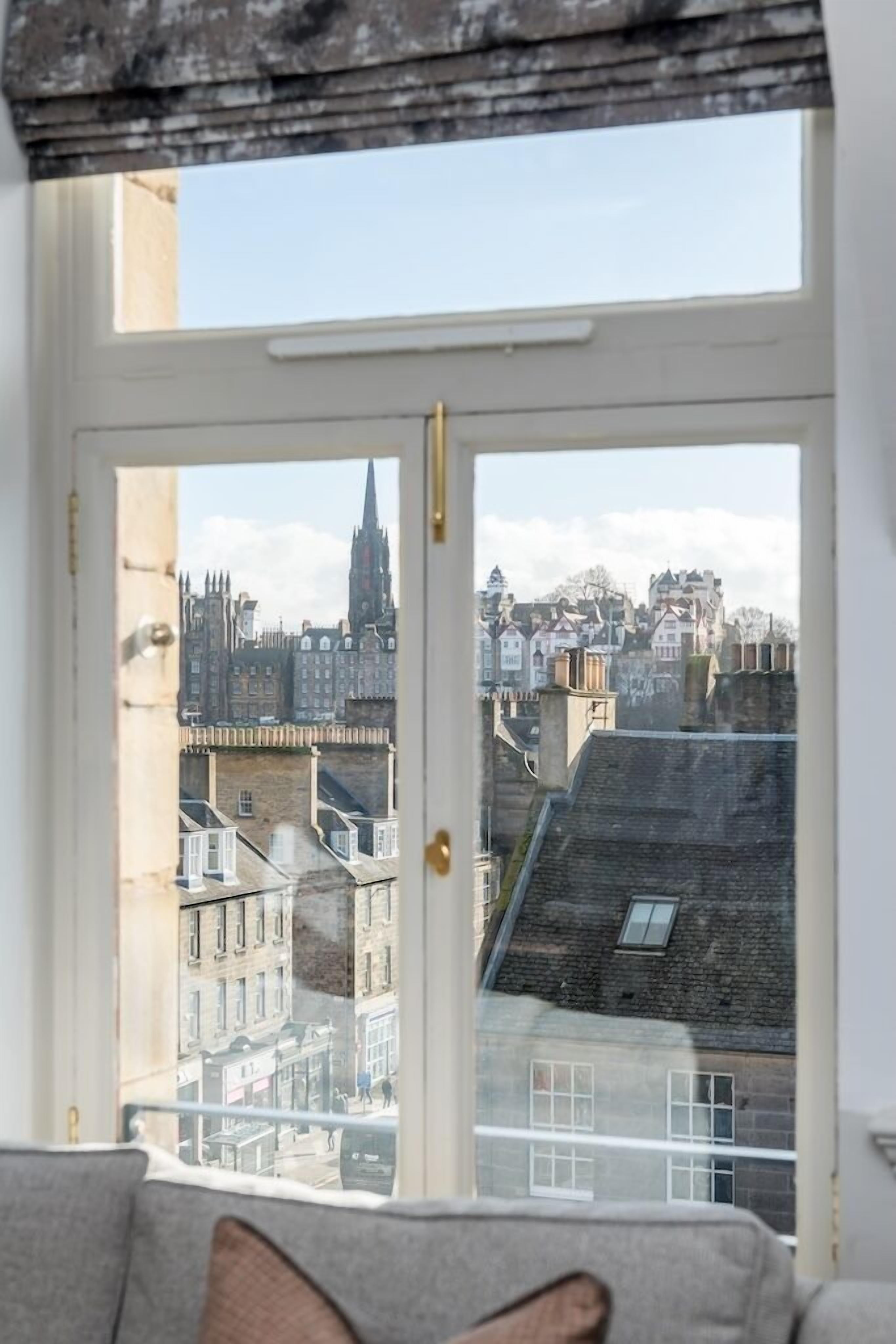A room with a large window overlooking a cityscape, including historic buildings and a church spire.
