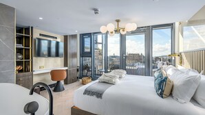 Une chambre d’hôtel moderne, dotée d’un grand lit, d’un bureau, d’une chaise et d’un téléviseur fixé au mur.