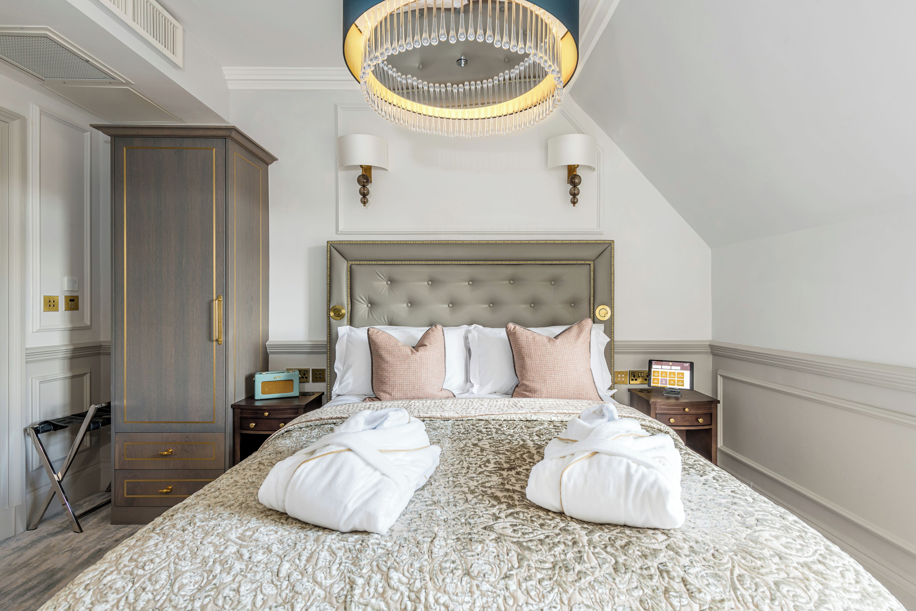 Une chambre spacieuse avec un grand lit, un lustre et une armoire.