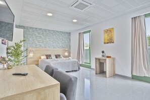 A modern hotel room with a bed, a desk, a chair, a small table, a globe, and a plant. - Les Begues Apartments (Begues)