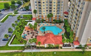A high-rise hotel with a swimming pool, multiple balconies, and a parking lot. - Universal-Disney Dream 1 Bedroom (Orlando)