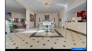 A spacious lobby with a central reception desk, a chandelier, and a patterned floor. - Universal-Disney Dream 2 Bedroom (Orlando)