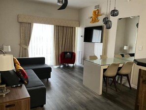 Een moderne hotelkamer met een zithoek, een eethoek en een grote spiegel.