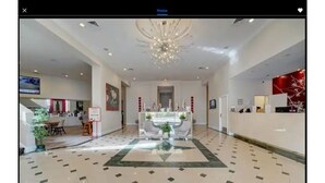 Un hall d’entrée spacieux avec un espace salon central, un lustre et un comptoir d’accueil.